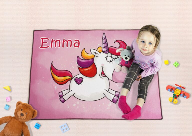 Pinker Einhornteppich mit dem Namen Emma, auf dem ein kleines Mädchen sitzt